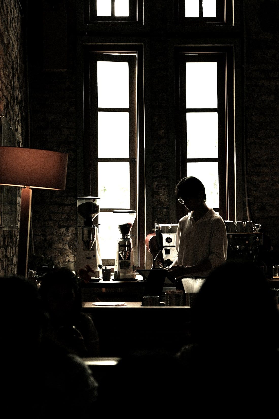 The counter at the window: two grinders, the brew tray, and customers seated in front of it.